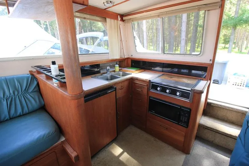 Slide: The Image of 1989 Tollycraft 30 Sport Cruiser kitchen with wood cabinetry, sink, stove, and microwave. - 17