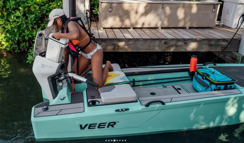 Slide: The Image of Person preparing Veer V13 boat, 2024 model, at dock with gear and cooler. - 3