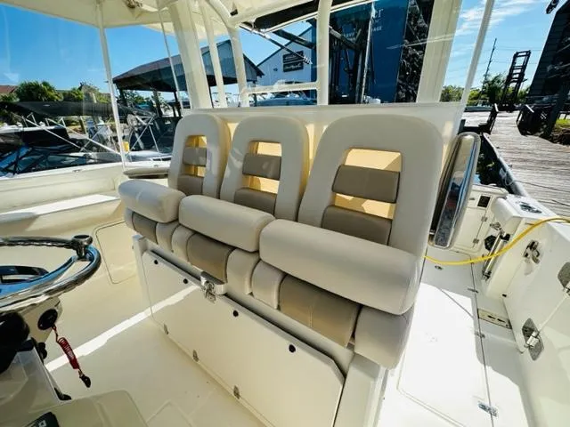 Slide: The Image of 2023 Boston Whaler 360 Outrage boat interior with cushioned seating and steering wheel. - 19