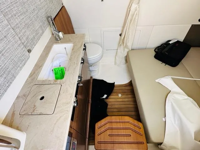 Slide: The Image of 2023 Boston Whaler 360 Outrage cabin interior with sink, toilet, and seating area. - 29
