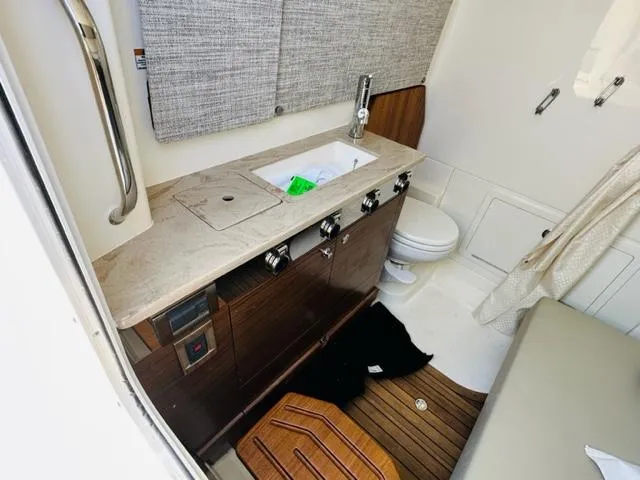 Slide: The Image of 2023 Boston Whaler 360 Outrage boat interior with sink, toilet, and wooden cabinetry. - 31