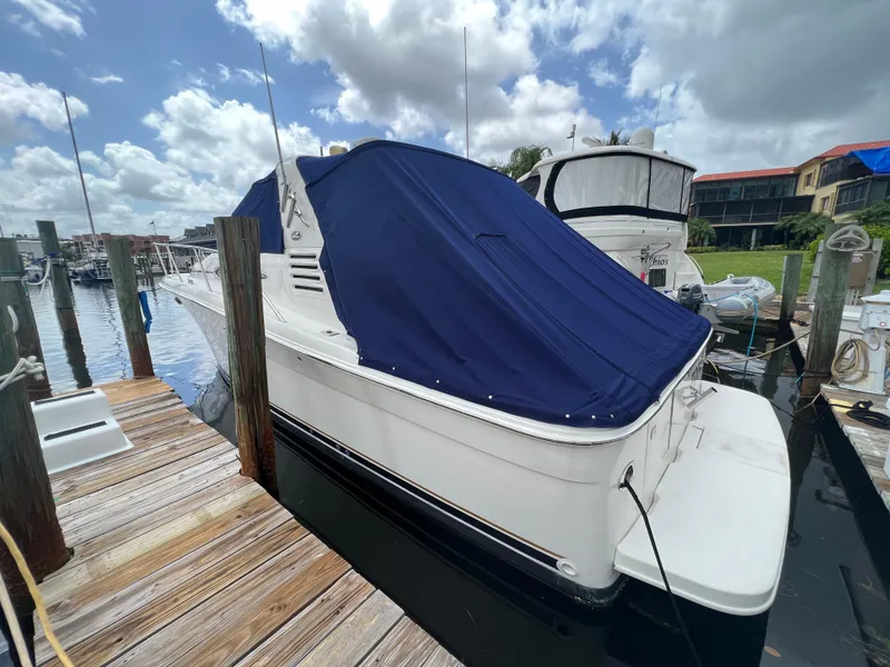 Slide: The Image of 2001 Sea Ray 340 Amberjack docked with blue cover, wooden pier, and cloudy sky. - 2