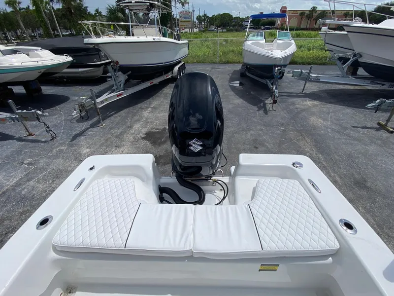 Slide: The Image of 2024 Savannah SS19 boat with outboard motor and cushioned seating, docked among other boats. - 18