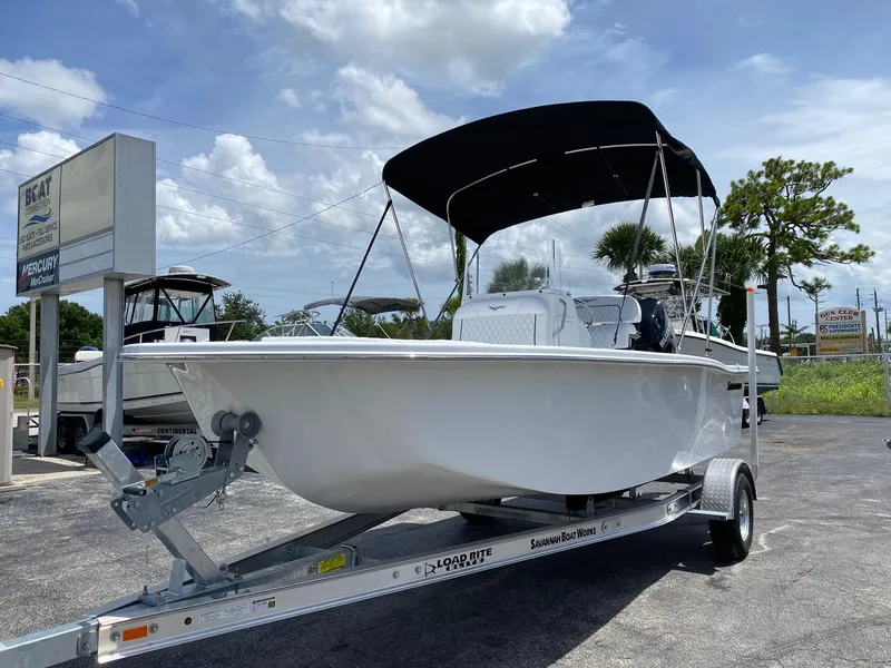 Slide: The Image of 2024 Savannah SS19 boat on trailer with black canopy, displayed outdoors. - 2