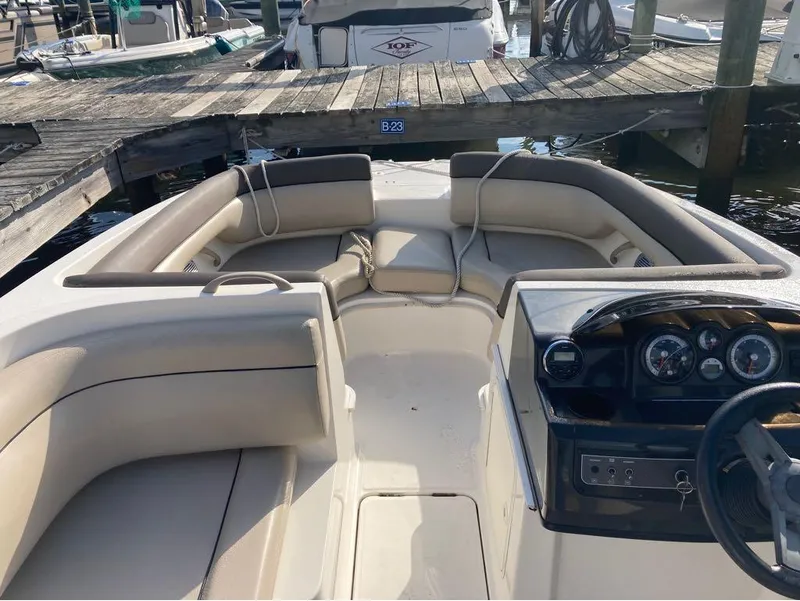 Slide: The Image of 2017 Bayliner 190 boat interior with beige seating and dashboard at a marina. - 5