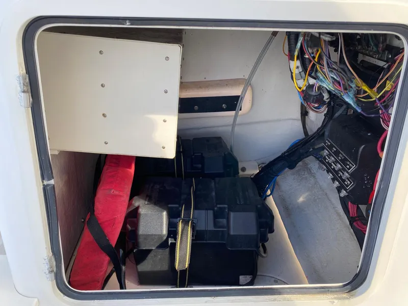 Slide: The Image of 2004 Boston Whaler 210 Outrage battery compartment with wiring and storage. - 11