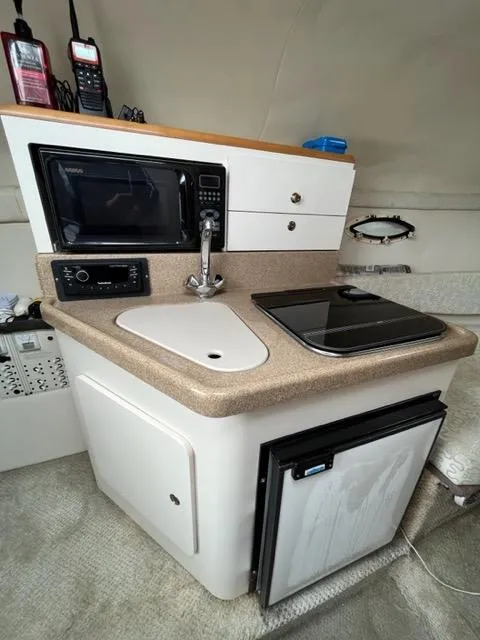 Slide: The Image of Compact kitchen area in 2002 Larson 254 Cabrio boat with microwave, sink, and mini-fridge. - 11
