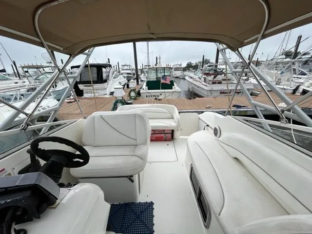 Slide: The Image of 2002 Larson 254 Cabrio boat interior at marina, featuring white seating and steering wheel. - 3