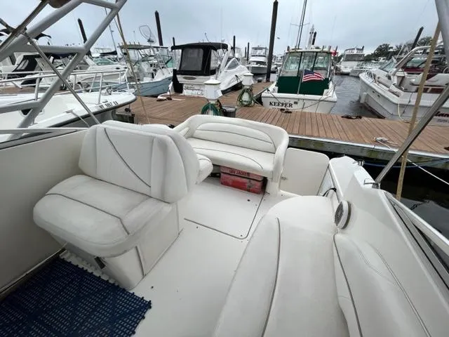 Slide: The Image of 2002 Larson 254 Cabrio boat interior with white seating at a marina. - 5
