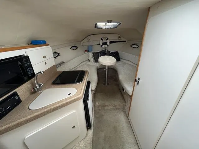 Slide: The Image of 2002 Larson 254 Cabrio boat interior with kitchenette and seating area. - 8