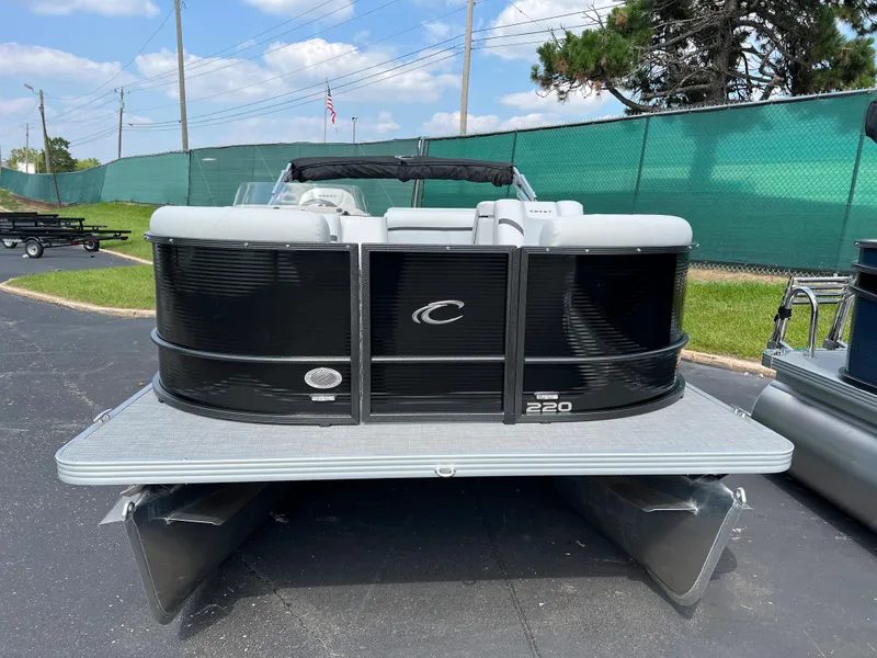 Slide: The Image of 2024 Crest Classic LX 220 pontoon boat with black exterior, docked on pavement. - 3