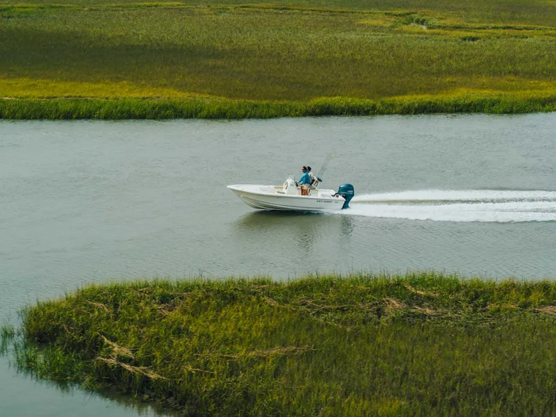 Slide: The Image of 2024 Key West 188 Bay Reef boat cruising on a river surrounded by lush greenery. - 17