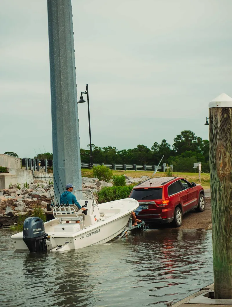 Slide: The Image of 2024 Key West 188 Bay Reef boat being launched from a red SUV at a boat ramp. - 27