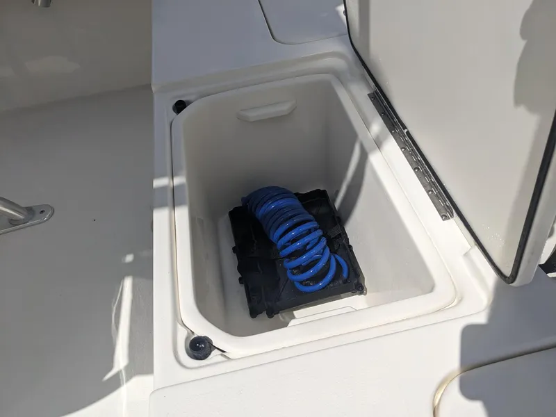 Slide: The Image of 2024 Key West 188 Bay Reef storage compartment with blue coiled hose. - 6
