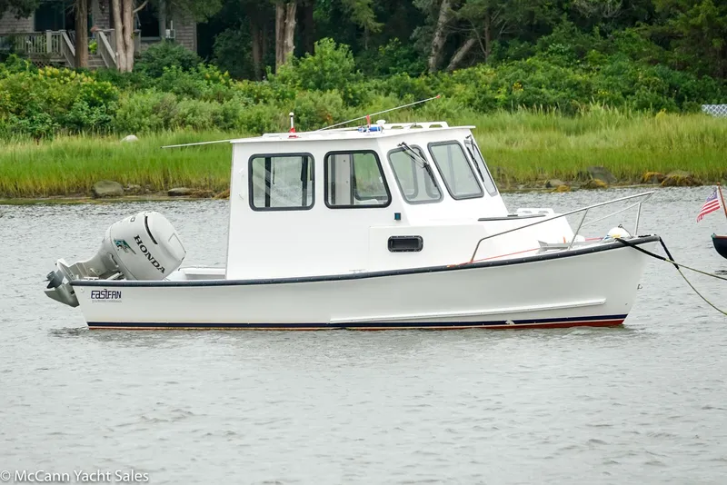 Slide: The Image of 2002 Eastern Lobsterman 22 boat on calm water, with lush greenery in the background. - 5