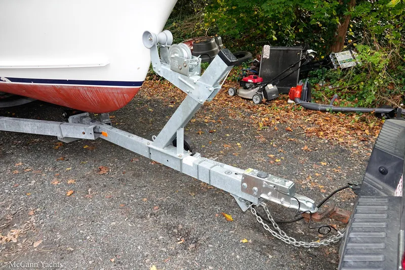 Slide: The Image of Trailer hitch of a 2002 Eastern Lobsterman 22 boat, parked on gravel with foliage background. - 16