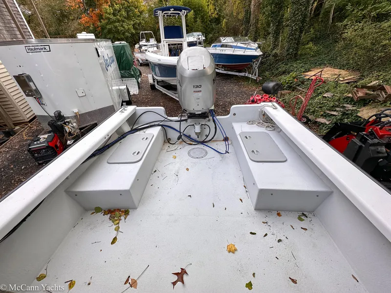 Slide: The Image of 2002 Eastern Lobsterman 22 boat with outboard motor, parked outdoors among trees and equipment. - 8