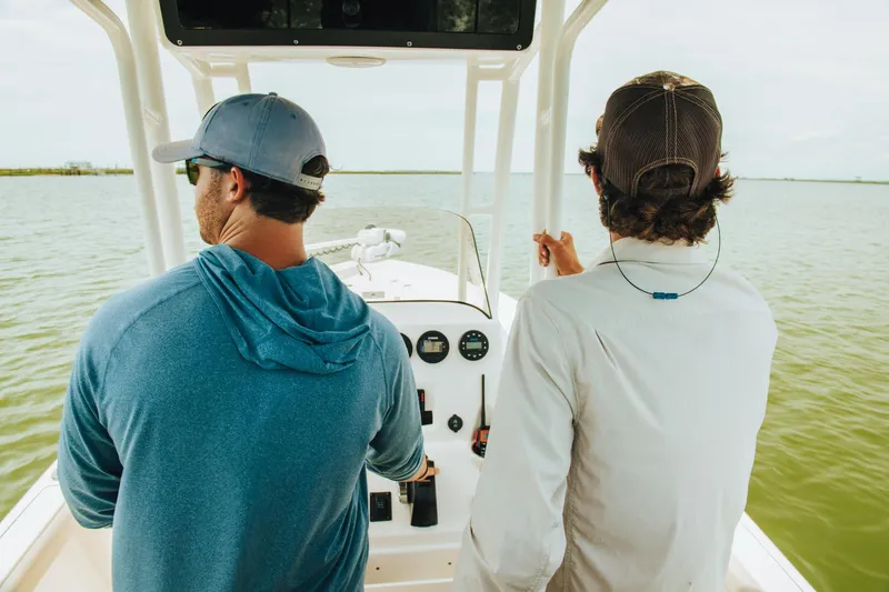 Slide: The Image of Two men navigating a 2024 Key West 230 Bay Reef boat on calm waters. - 33