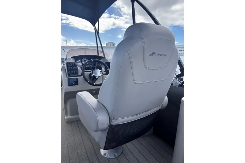 Slide: The Image of Captain's seat and helm of 2023 Starcraft CX 23 DL BAR boat under a blue sky. - 28
