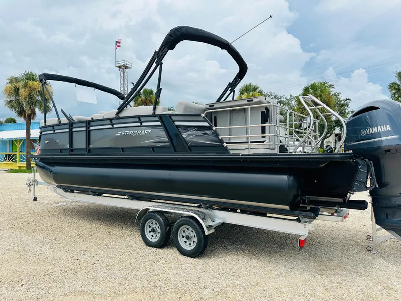 Slide: The Image of 2023 Starcraft CX 23 DL BAR pontoon boat on trailer, under cloudy sky. - 4