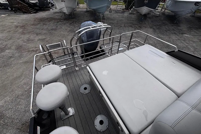 Slide: The Image of 2023 Starcraft CX 23 DL BAR boat interior with seating and motor, parked on pavement. - 48