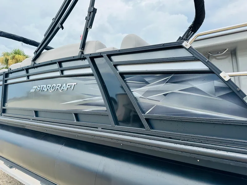 Slide: The Image of 2023 Starcraft CX 23 DL BAR pontoon boat on trailer, black canopy, overcast sky. - 5