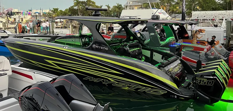 Slide: The Image of 2023 Mystic Powerboats M4200 at a boat show, featuring sleek black and green design. - 13