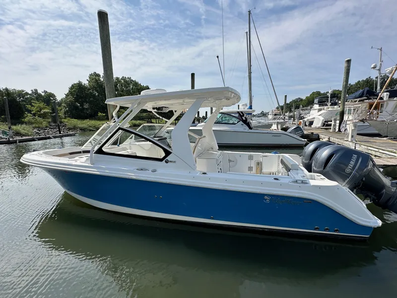 Slide: The Image of 2018 Edgewater 262CX boat docked in a marina, featuring a blue hull and twin engines. - 1