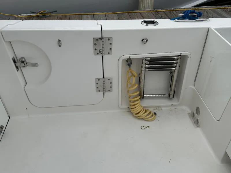 Slide: The Image of 2018 Edgewater 262CX boat deck with storage compartments and coiled hose. - 10