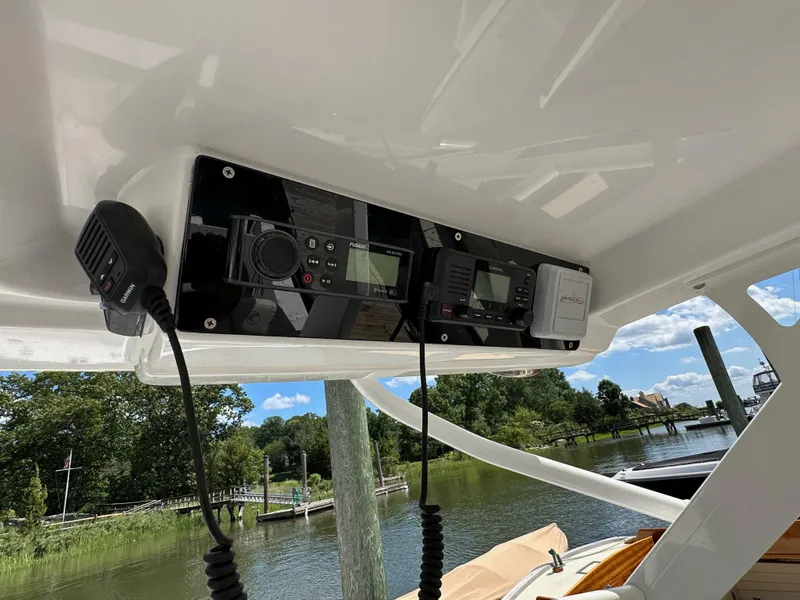 Slide: The Image of Edgewater 262CX 2018 boat console with communication equipment, docked by a scenic riverside. - 6