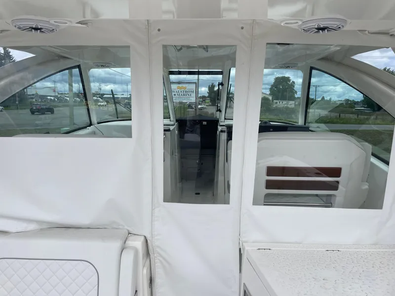Slide: The Image of 2024 Pursuit DC 326 Dual Console boat interior with white seating and clear windows. - 10