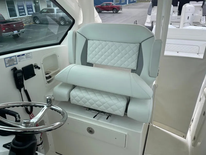 Slide: The Image of 2024 Pursuit DC 326 Dual Console boat interior with white quilted seating and steering wheel. - 13