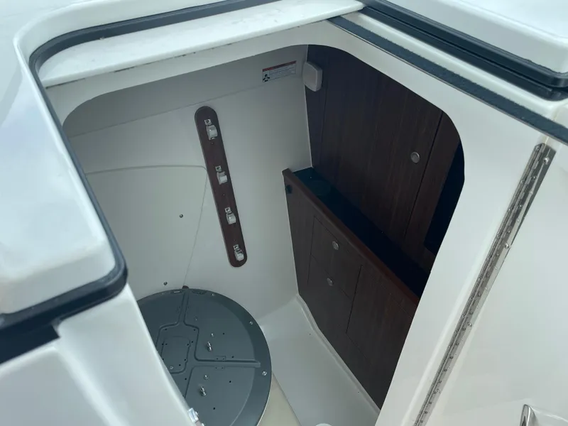 Slide: The Image of 2024 Pursuit DC 326 Dual Console interior storage compartment with wooden paneling. - 14