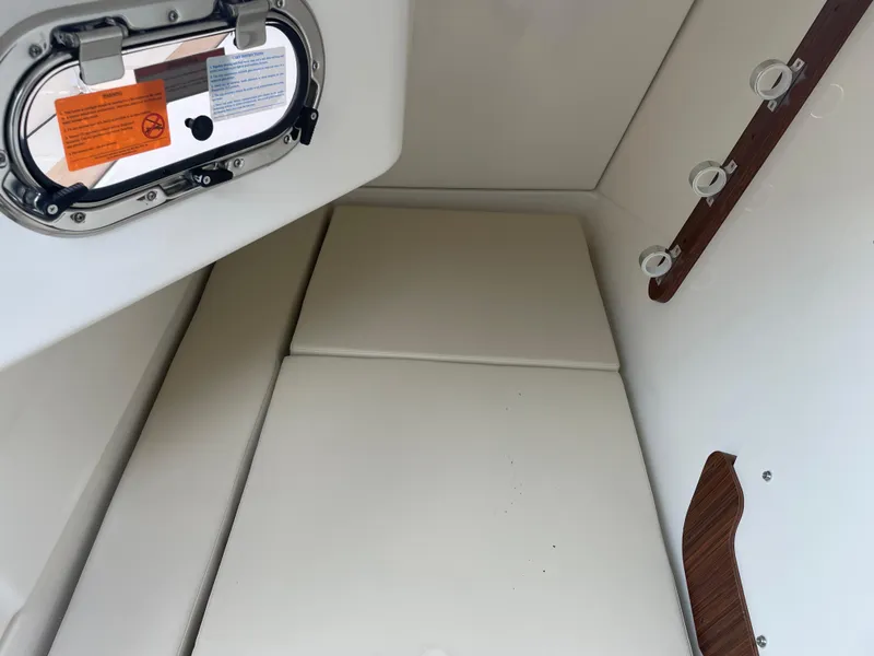 Slide: The Image of 2024 Pursuit DC 326 Dual Console cabin interior with cushioned seating and porthole. - 15