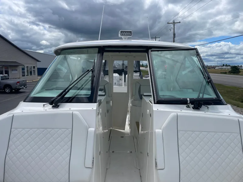 Slide: The Image of 2024 Pursuit DC 326 Dual Console boat with windshield and open deck, under cloudy sky. - 24