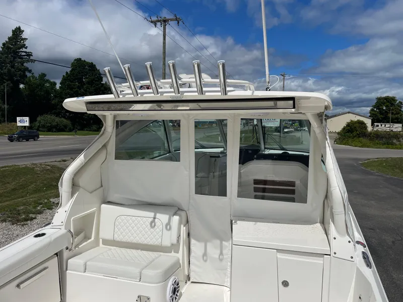 Slide: The Image of 2024 Pursuit DC 326 Dual Console boat, featuring spacious seating and rod holders, under a clear sky. - 4