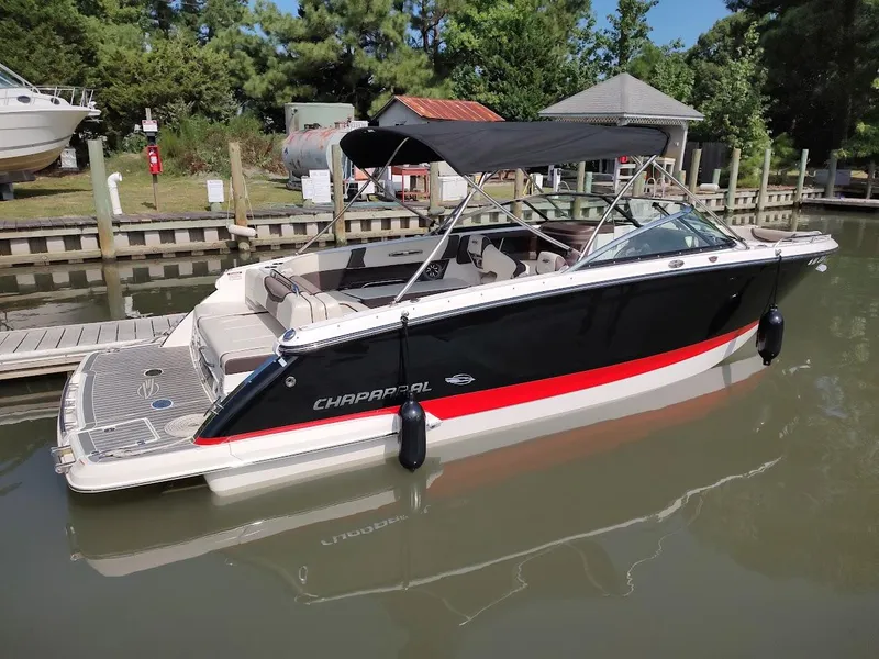 The Image of 2018 Chaparral 267 SSX boat docked in a marina, featuring sleek black and red design. - 0