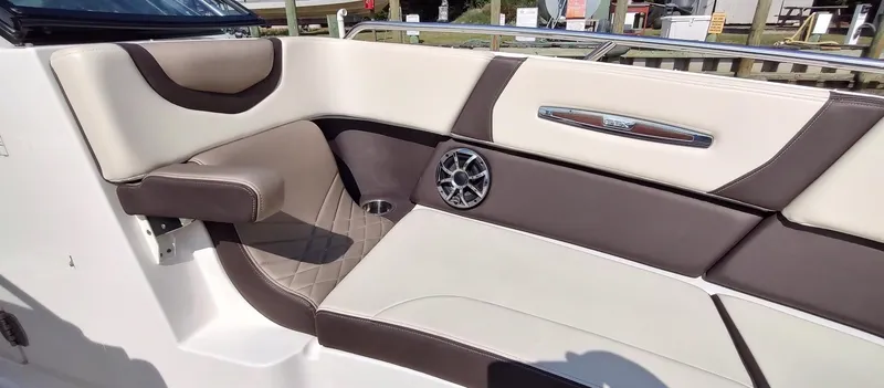Slide: The Image of 2018 Chaparral 267 SSX boat interior with beige and brown seating, featuring a speaker and armrest. - 16