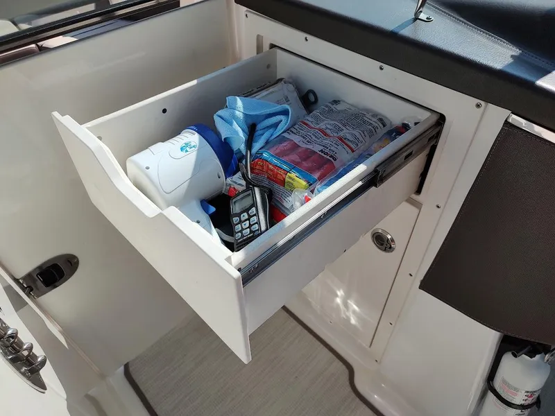 Slide: The Image of Open storage drawer in 2018 Chaparral 267 SSX boat with various items inside. - 28