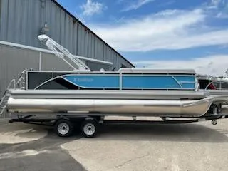 Slide: The Image of 2024 Sweetwater 2286SFL pontoon boat parked outside a warehouse. - 2