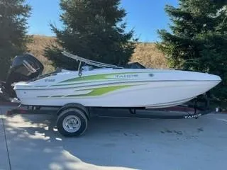 The Image of 2024 Tahoe T18 boat on trailer, white with green accents, parked outdoors. - 0