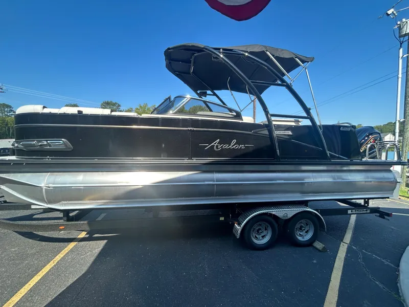 Slide: The Image of 2023 Avalon 2585 EL pontoon boat on a trailer under a clear blue sky. - 4