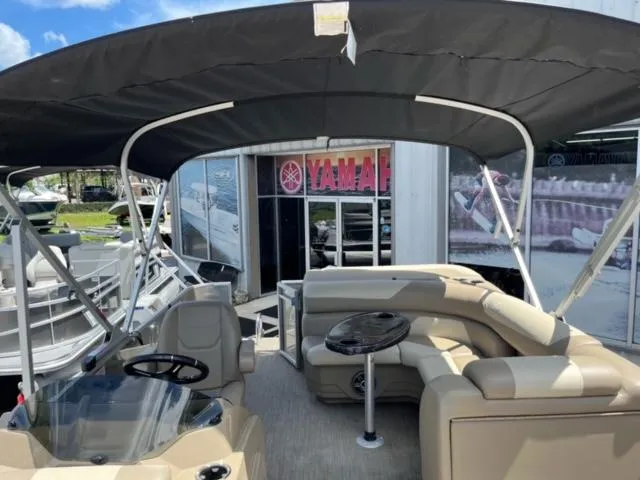 Slide: The Image of 2024 SunChaser Geneva Cruise 20 pontoon boat with canopy and seating, displayed at dealership. - 18