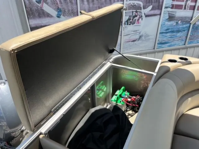Slide: The Image of 2024 SunChaser Geneva Cruise 20 boat storage compartment with open seat and visible battery. - 21