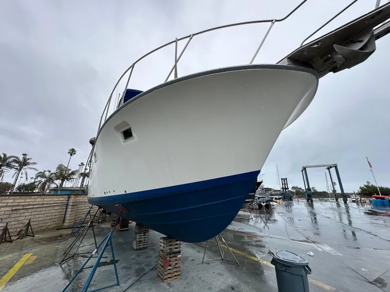Slide: The Image of 1981 Bertram 38III Convertible boat on dry dock, overcast sky, marina background. - 2