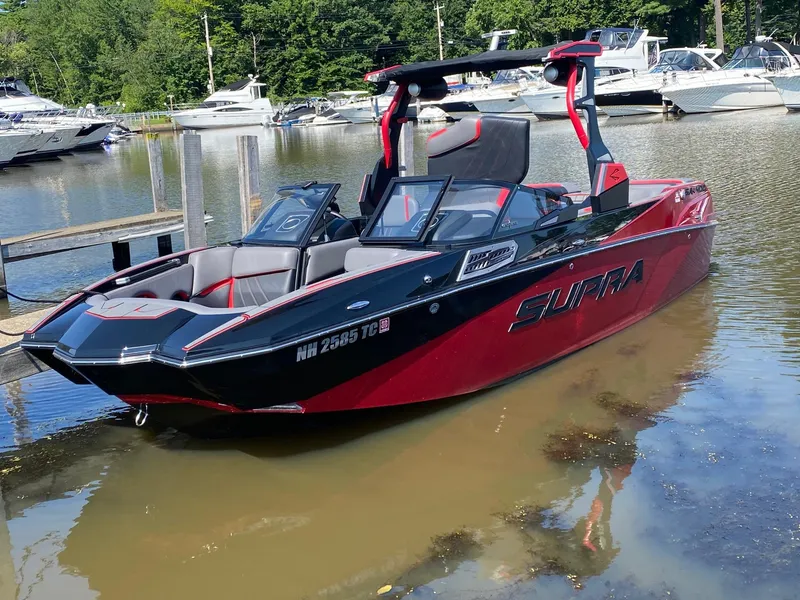 Slide: The Image of 2023 Supra SA boat docked in a marina with other boats in the background. - 0