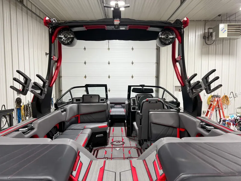 Slide: The Image of 2023 Supra SA boat interior in a garage, featuring red and gray seating and advanced audio system. - 11