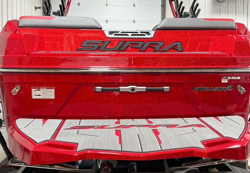 Slide: The Image of 2023 Supra SA boat rear view with red glitter finish and Swell Surf system. - 2