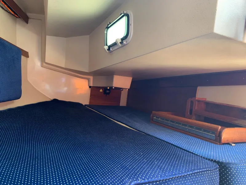 Slide: The Image of Interior cabin of 1987 Catalina 30 Tall-Rig sailboat with blue cushions and porthole. - 35