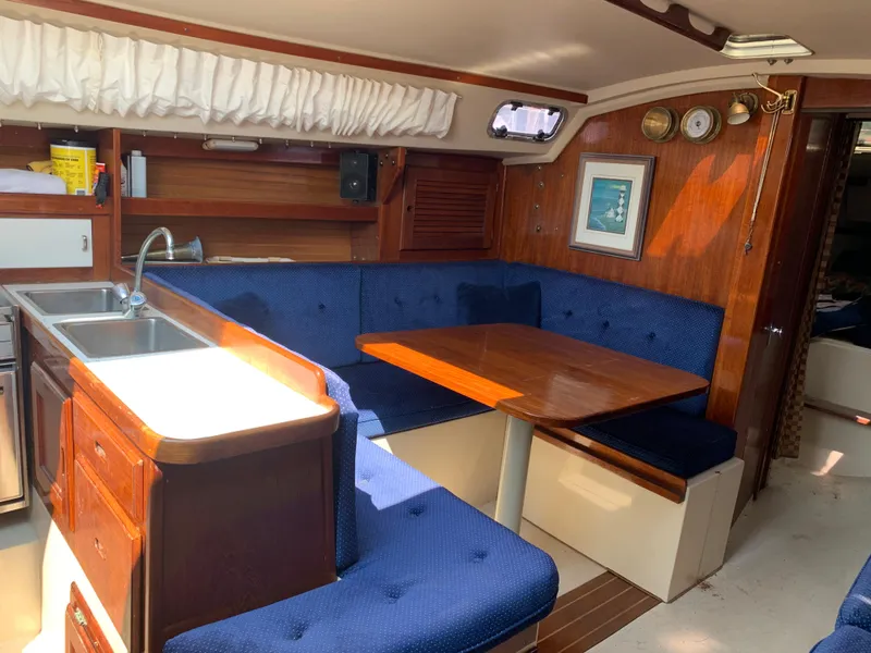 Slide: The Image of Interior of 1987 Catalina 30 Tall-Rig sailboat with blue seating and wooden table. - 45